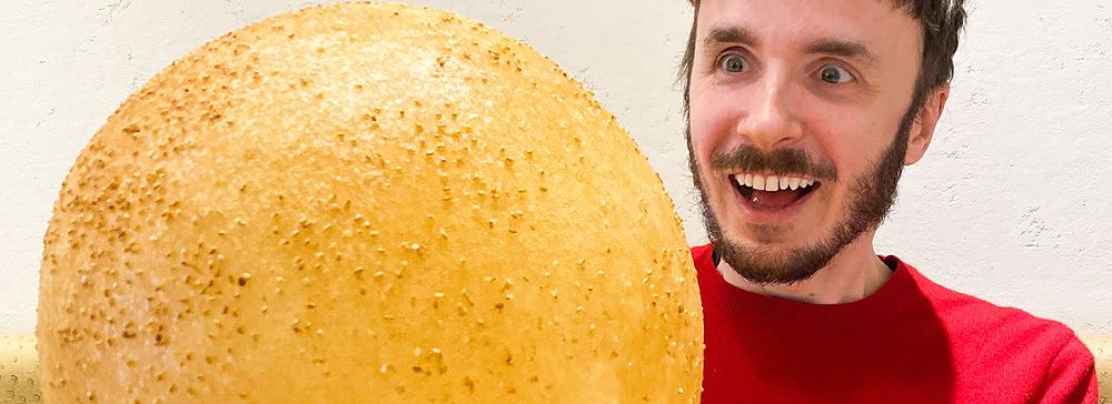 Marco Togni tiene in mano una gigantesca palla fritta al sesamo, un dolce servito al ristorante Mara Daigaku a Ueno.