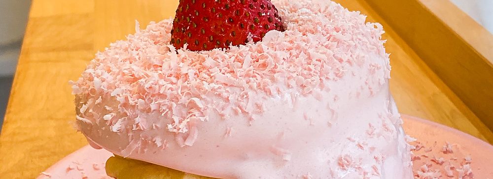 Un soffice pancake alla fragola con crema rosa e fragola fresca sopra un piatto rosa al Belle Epoque.