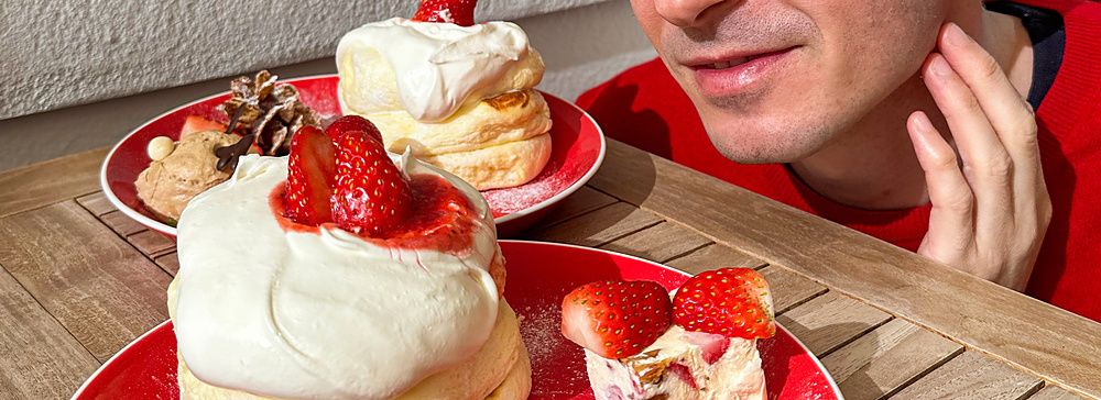 Marco Togni guarda con curiosità due piatti rossi contenenti pancake di Natale a Chaka decorati con fragole e crema.