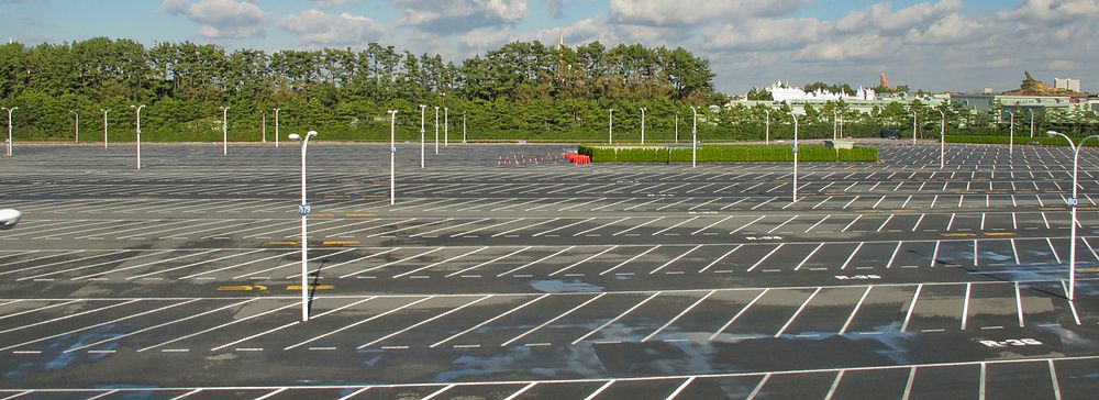 Parcheggio vuoto a Tokyo Disneyland con un'auto rossa.