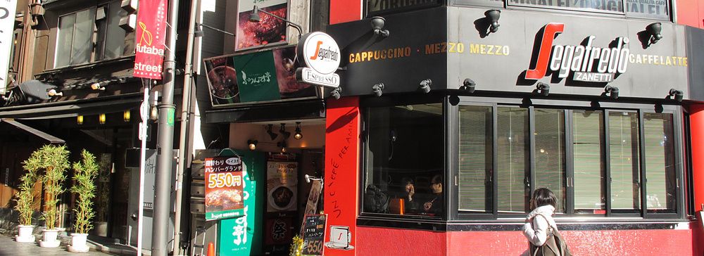 Persona cammina davanti a un caffè Segafredo a Shinjuku, Tokyo.