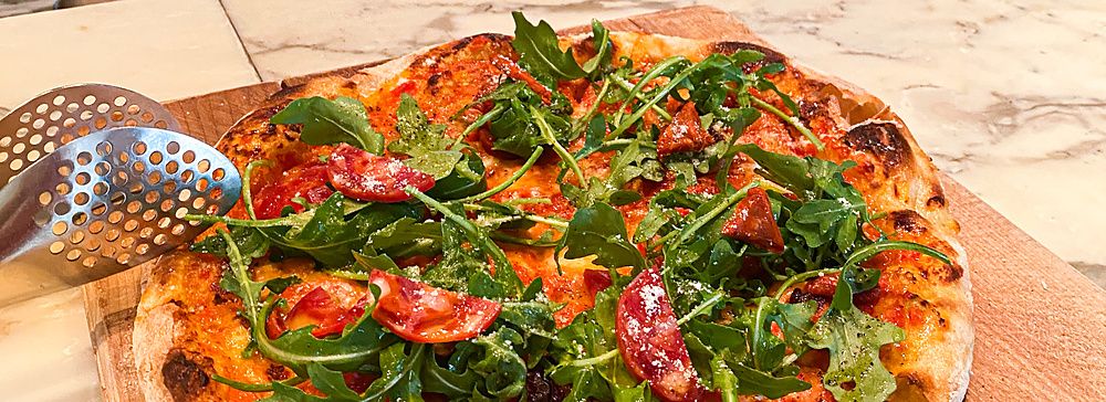 Una pizza con salame e rucola su un tagliere di legno al The Pizza Bar On 38th nel Mandarin Oriental Hotel di Tokyo.