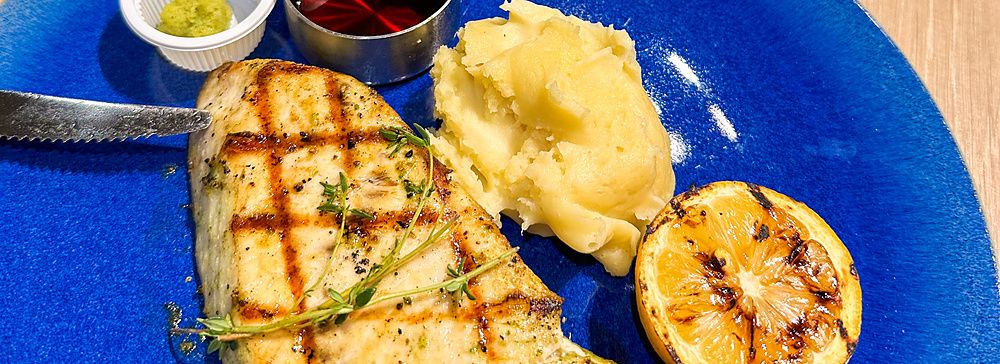 Un piatto con pollo a Sizzler grigliato, purè di patate e limone su un tavolo di legno nel ristorante Sizzler.