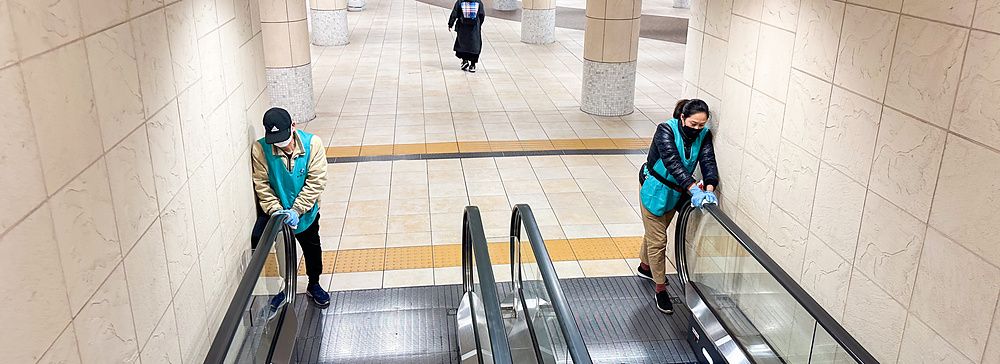 due addetti puliscono le scale mobili in uno spazio pubblico.