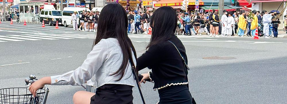 Due ragazze in bicicletta fermate a un incrocio a Ueno, Tokyo.