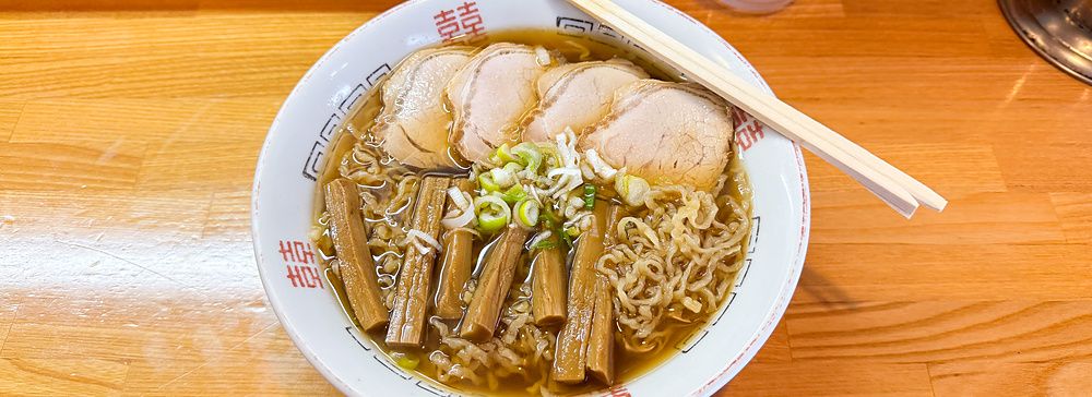 Una ciotola di ramen con maiale e bambù servita su un bancone di legno presso Midoriya Ramen a Hirosaki.