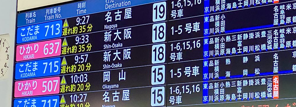 Un tabellone informativo in una stazione mostra treni Shinkansen in ritardo.