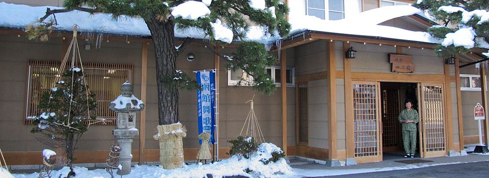 Facciata innevata del ryokan Ichinomatsu a Hakodate con una persona all'ingresso.