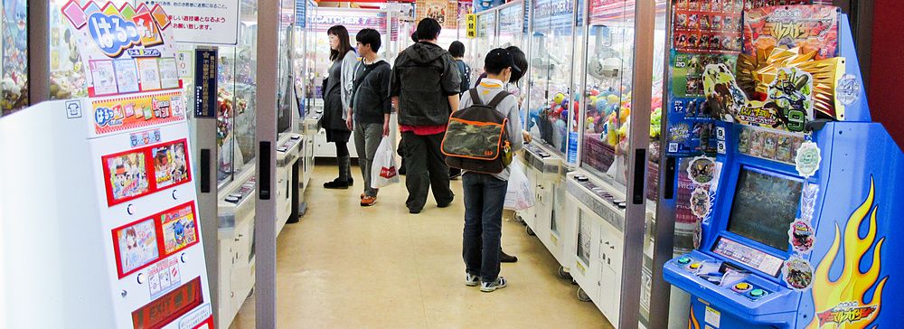 Sala giochi in Giappone con persone che giocano alle macchine a premi.
