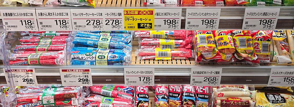 Confezioni di salsicce di pesce e snack per bambini esposte negli scaffali di un supermercato a Beppu.