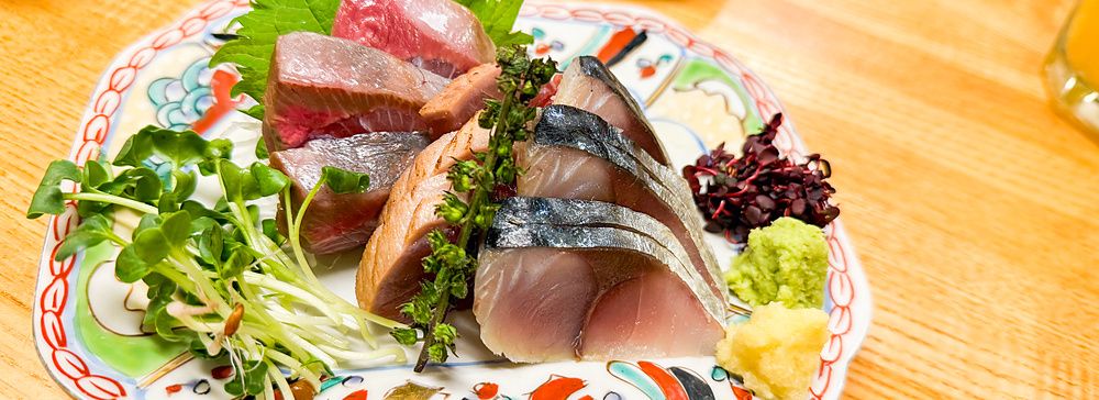 Sashimi assortito servito in un piatto decorato presso l'izakaya Hatonoyu a Tokyo.
