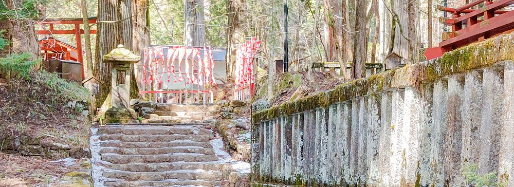 Santuario shintoista di Takinoo a Nikko con una scalinata in pietra innevata e un muro di cinta in pietra antica.