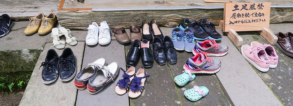 Varie paia di scarpe lasciate all'ingresso di una costruzione in legno durante una visita in Giappone.