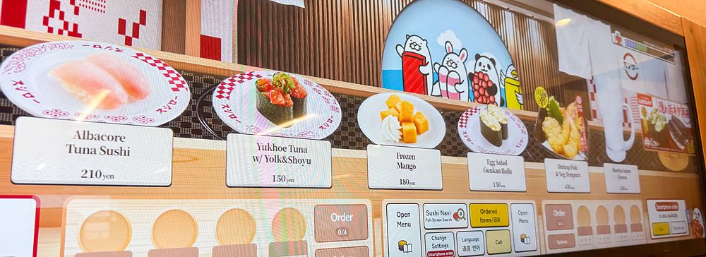 Uno schermo per ordinare a Sushiro con immagini di piatti di sushi e dessert selezionabili tramite interfaccia touch.