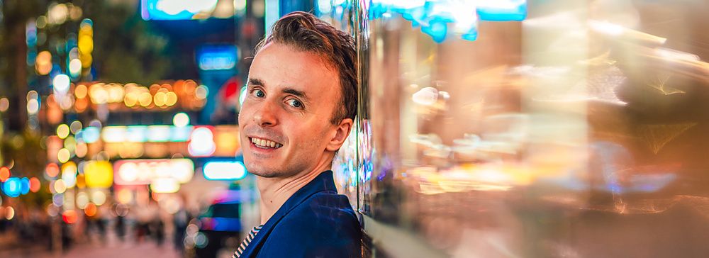 Marco Togni appoggiato a un muro illuminato dai neon a Ginza.