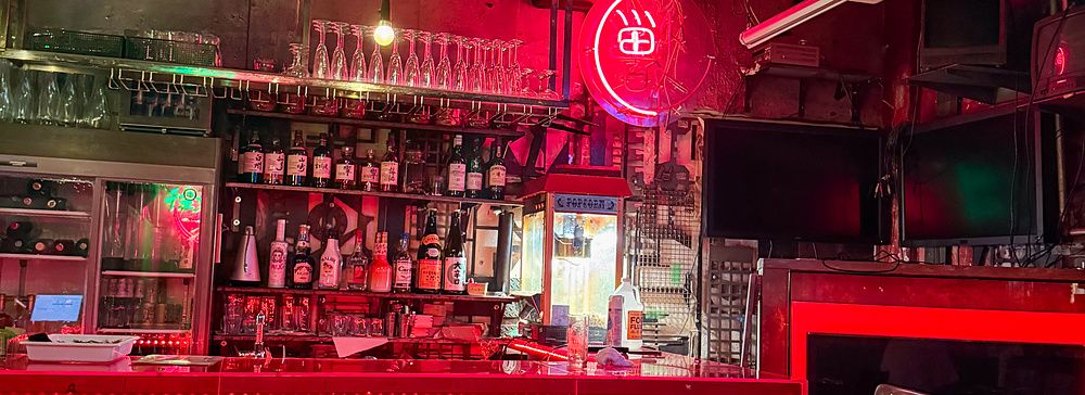 Interno del ristorante Neo Shinjuku Atsushi a Shinjuku, caratterizzato da luci al neon rosse e un hamburger vegano.
