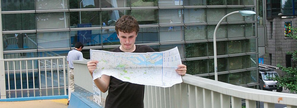 Una persona su un ponte pedonale a Shinjuku con una mappa.