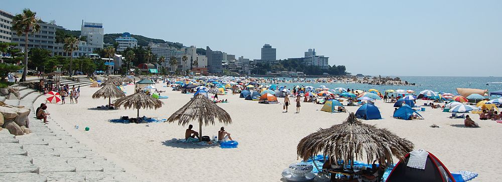 Spiaggia affollata di ombrelloni e persone a Shirahama Beach, Giappone.