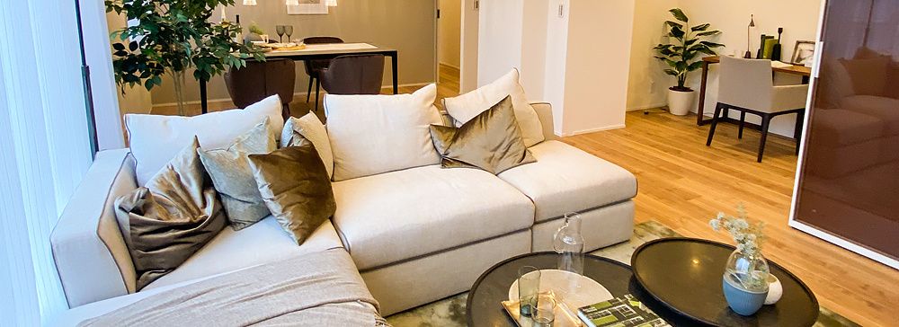 Un elegante soggiorno con divano angolare bianco e tavolini in un appartamento di lusso a Tokyo.