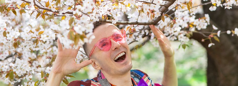 Marco Togni sorridente sotto un albero di ciliegio in fiore a Tokyo.