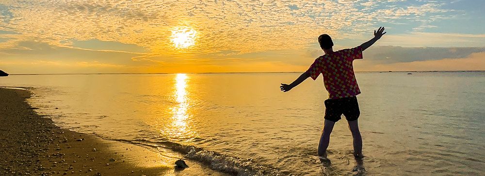 persona al tramonto sulla spiaggia Mimikiri con cielo nuvoloso.