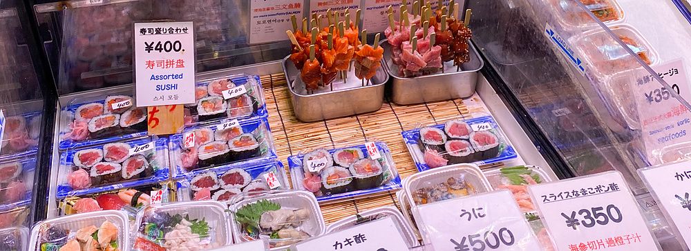 Spiedini di pesce crudo al mercato Nishiki di Kyoto con cartellini dei prezzi.