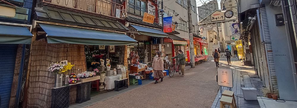 Veduta di una tipica strada storica del quartiere Yanaka a Tokyo con negozi e persone che camminano.