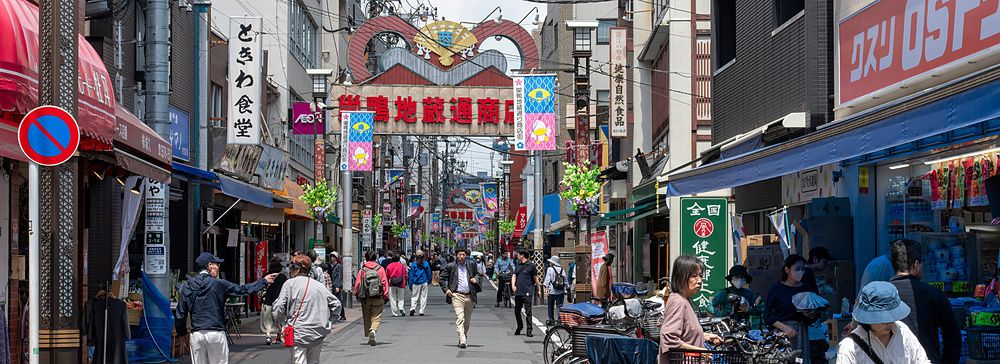Veduta prospettica della strada commerciale Sugamo Jizodori a Tokyo con pedoni e biciclette parcheggiate.