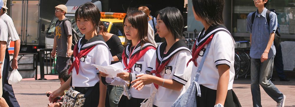 Gruppo di studentesse in uniforme cammina per strada in giappone.