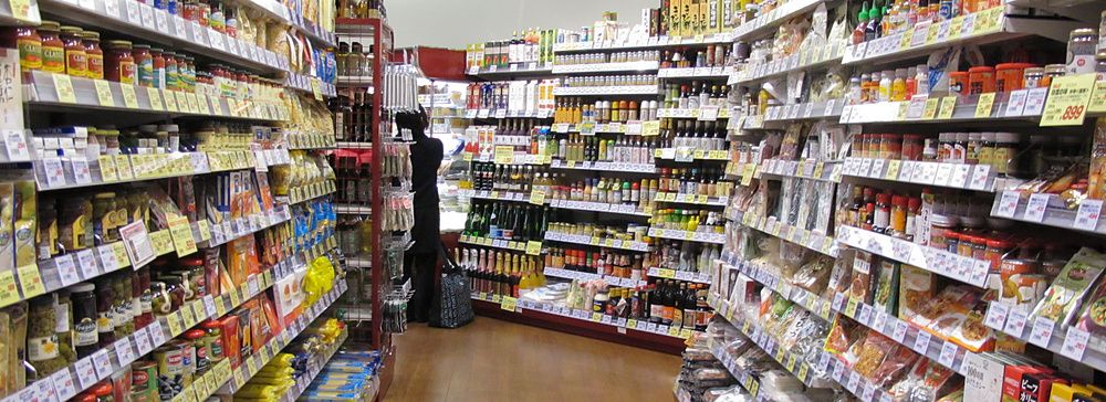 Corridoio di un supermercato Seijo Ishii in Giappone con scaffali colmi di prodotti alimentari e una persona.