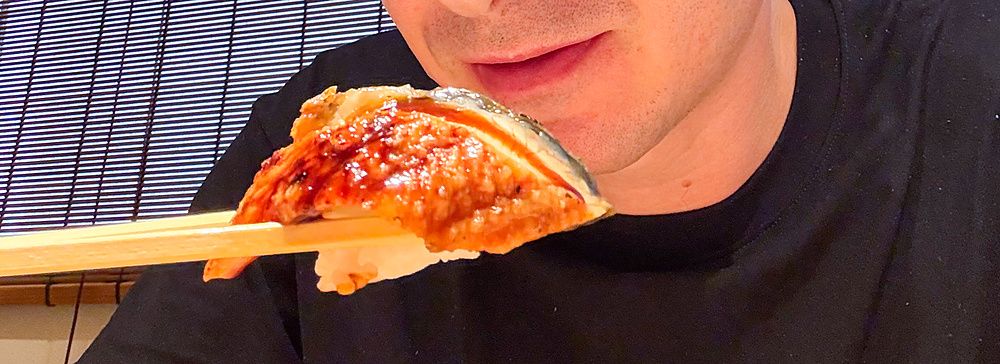 Marco Togni tiene in mano un pezzo di sushi con le bacchette all'interno del Ristorante New Sushi Center Harukiya a Osaka.