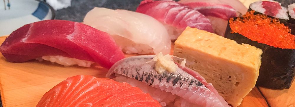 Un assortimento di nigiri e gunkan sushi servito su un tagliere di legno al ristorante Sushidokoro Okame a Tokyo.