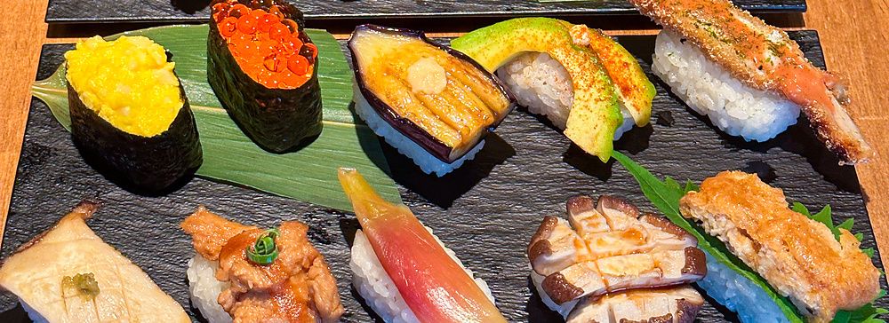 Assortimento di nigiri vegani serviti su piatti di ardesia nera presso il ristorante Vegan Sushi Tokyo a Shibuya.