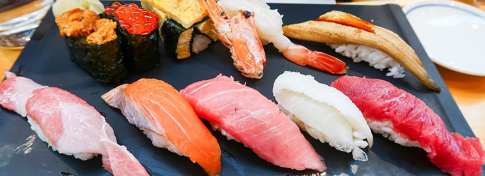 Assortimento di sushi su un vassoio nero al ristorante Sushi Zanmai.