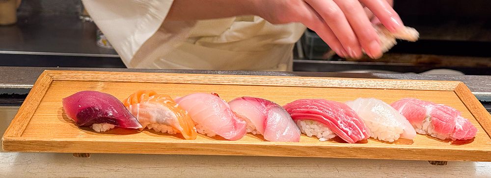 Un vassoio di legno con nigiri sushi freschi poggiato su un bancone presso il ristorante Sushimaru a Shinjuku.