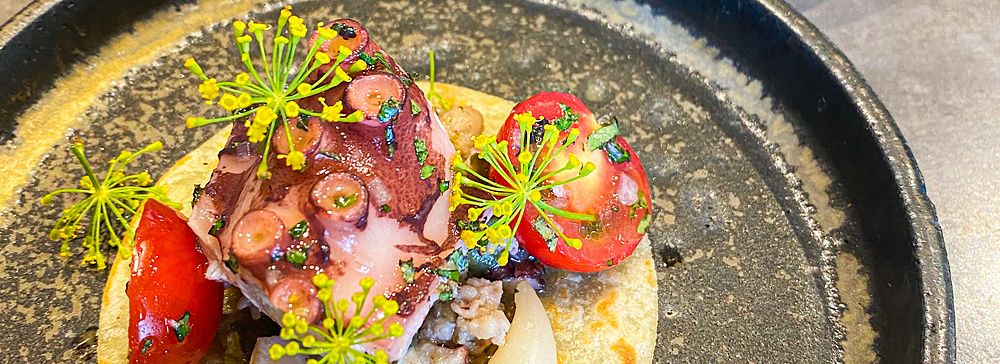 Taco morbido con polpo, pomodorini e capperi, servito accanto a un secondo di carne al ristorante Ode di Tokyo.