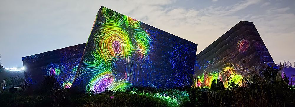 Installazione di luci colorate con vortici su strutture architettoniche nel teamLab Botanical Garden Osaka.