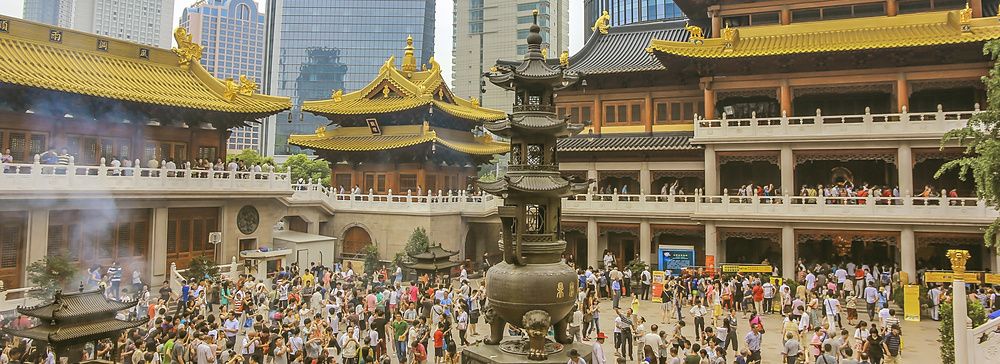 Folla di fedeli nel tempio buddhista Jing'an a Shanghai tra moderni grattacieli.