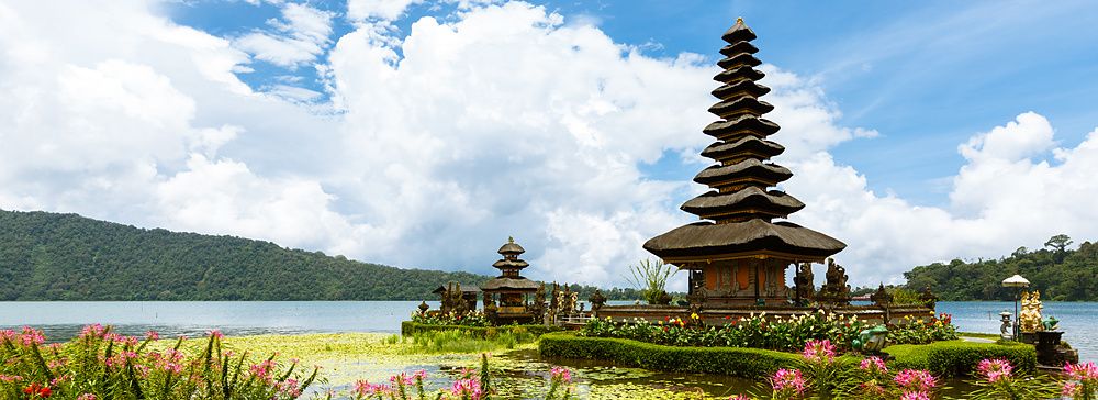 Il tempio Ulun Danu Bratan a Bali su un lago circondato da fiori e montagne.