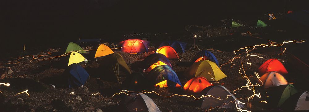 Tende colorate illuminate di notte con il monte Fuji sullo sfondo.