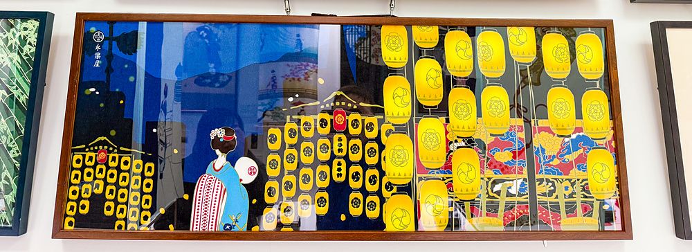 Una parete di un negozio Eirakuya a Kyoto con tenugui incorniciati che mostrano illustrazioni tradizionali giapponesi.