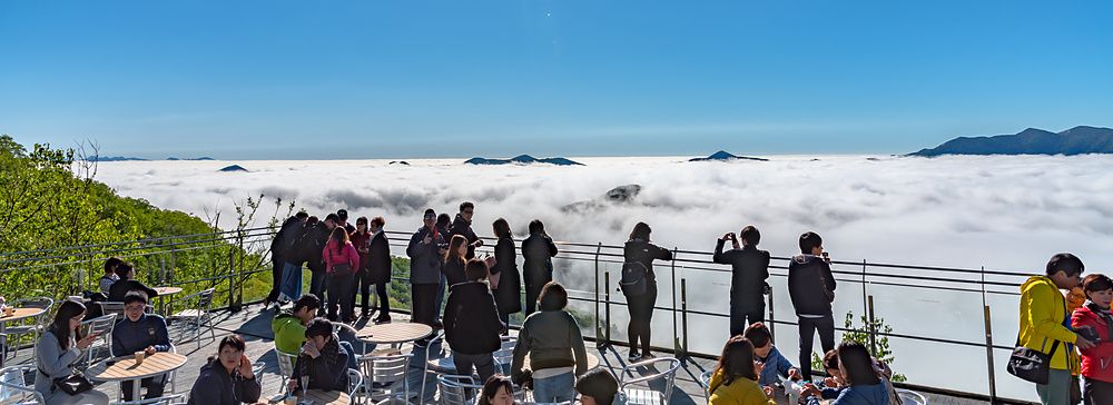 Turisti sulla terrazza panoramica di Unkai Terrace a Tomamu con il sole alto sopra un mare di nuvole.