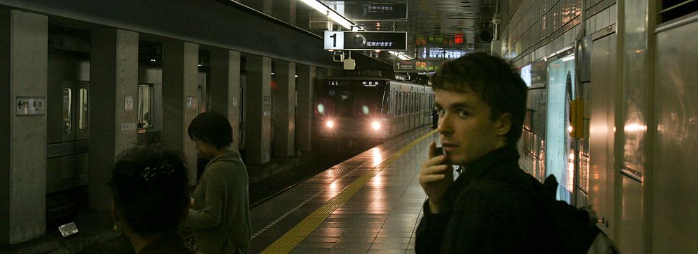 Una banchina della metropolitana a Tokyo con Marco Togni in primo piano e un treno che arriva in stazione.