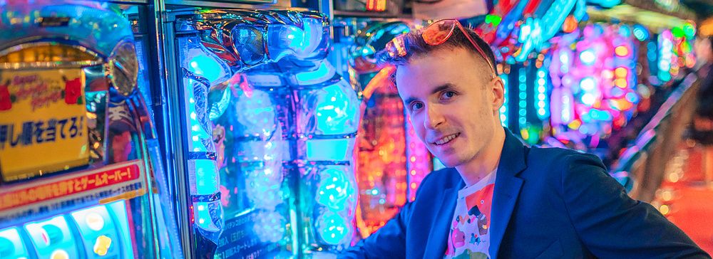 Marco Togni seduto davanti a macchine pachinko luminose in Giappone.