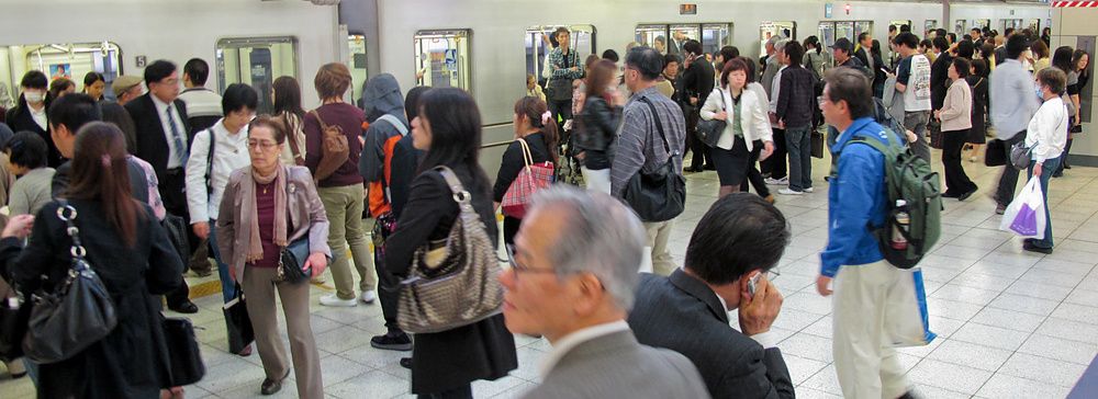 Stazione ferroviaria affollata in giappone con molte persone.