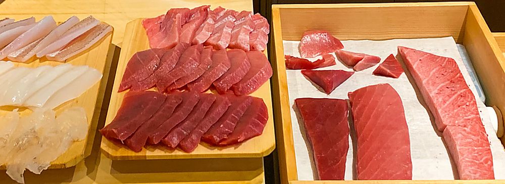Diversi tagli di tonno esposti su piatti a Sushi Masashi.
