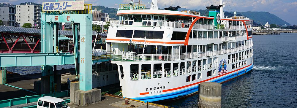 Il traghetto Sakurajima attraccato al molo di Kagoshima con un furgone bianco sulla banchina.