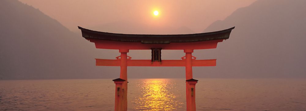 Torii rosso nel santuario di Miyajima al tramonto, Giappone.