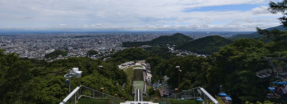 Veduta grandangolare della città di Sapporo vista dalla cima del trampolino olimpico di Okurayama in una giornata estiva.