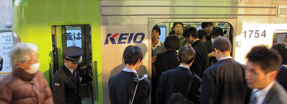 Persone in abiti formali salgono su un treno della linea Keio in Giappone.